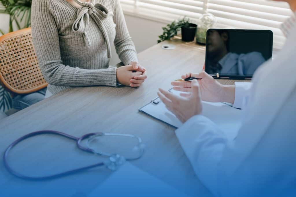 Patient sitting across a desk from a doctor during a medical consultation.
