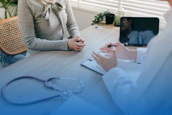 Patient sitting across a desk from a doctor during a medical consultation.