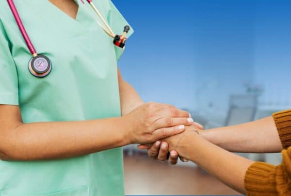 Healthcare provider holding hands with a patient in a supportive consultation, illustrating key questions to ask when diagnosed with breast cancer.