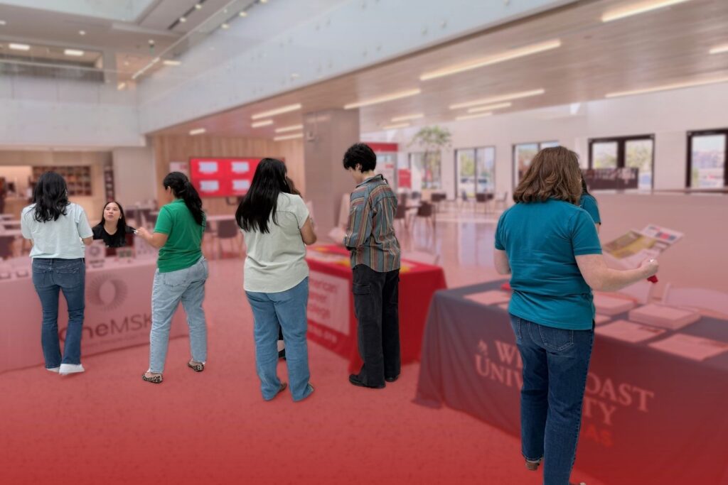 People gathered around informational booths and display tables inside an atrium during a health and wellness fair.